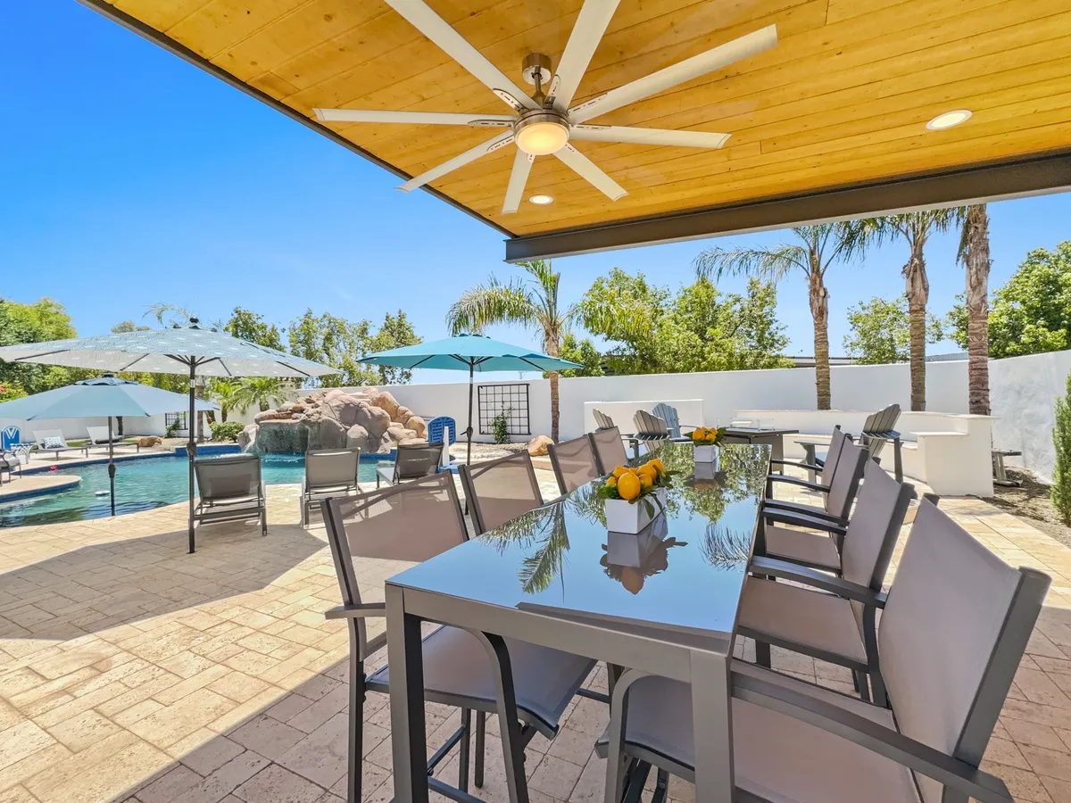A cheerful and inviting poolside dining area surrounded by lush palm trees and comfortable lounge seating. The scene is set for sunset dinners, casual brunches, or group celebrations by the water, exuding a relaxed, social energy.
