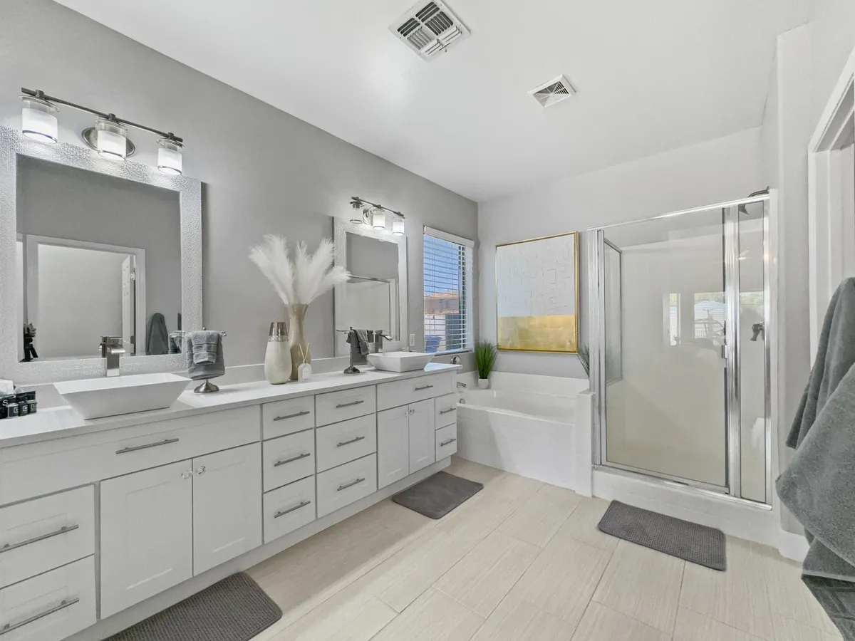 A luxurious bathroom with a double sink vanity, large mirrors, a bathtub, and glass shower enclosure. Clean lines and serene décor create a spa-like environment for self-care routines or a relaxing bath after a long day.