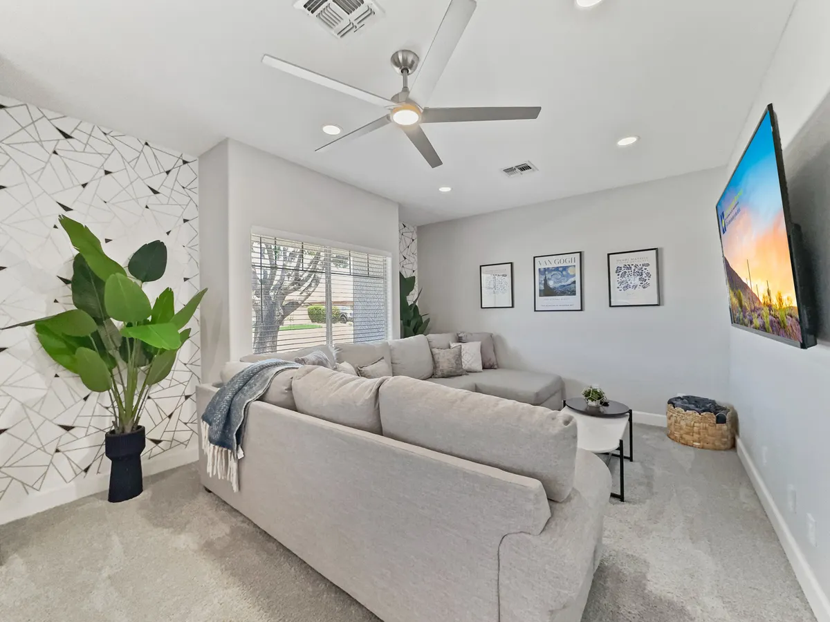 A modern living space with a large sectional sofa, geometric accent wall, indoor plant, and a TV with a scenic image. The expansive sectional is ideal for sleepovers and group lounging, conveying a sense of cozy togetherness.