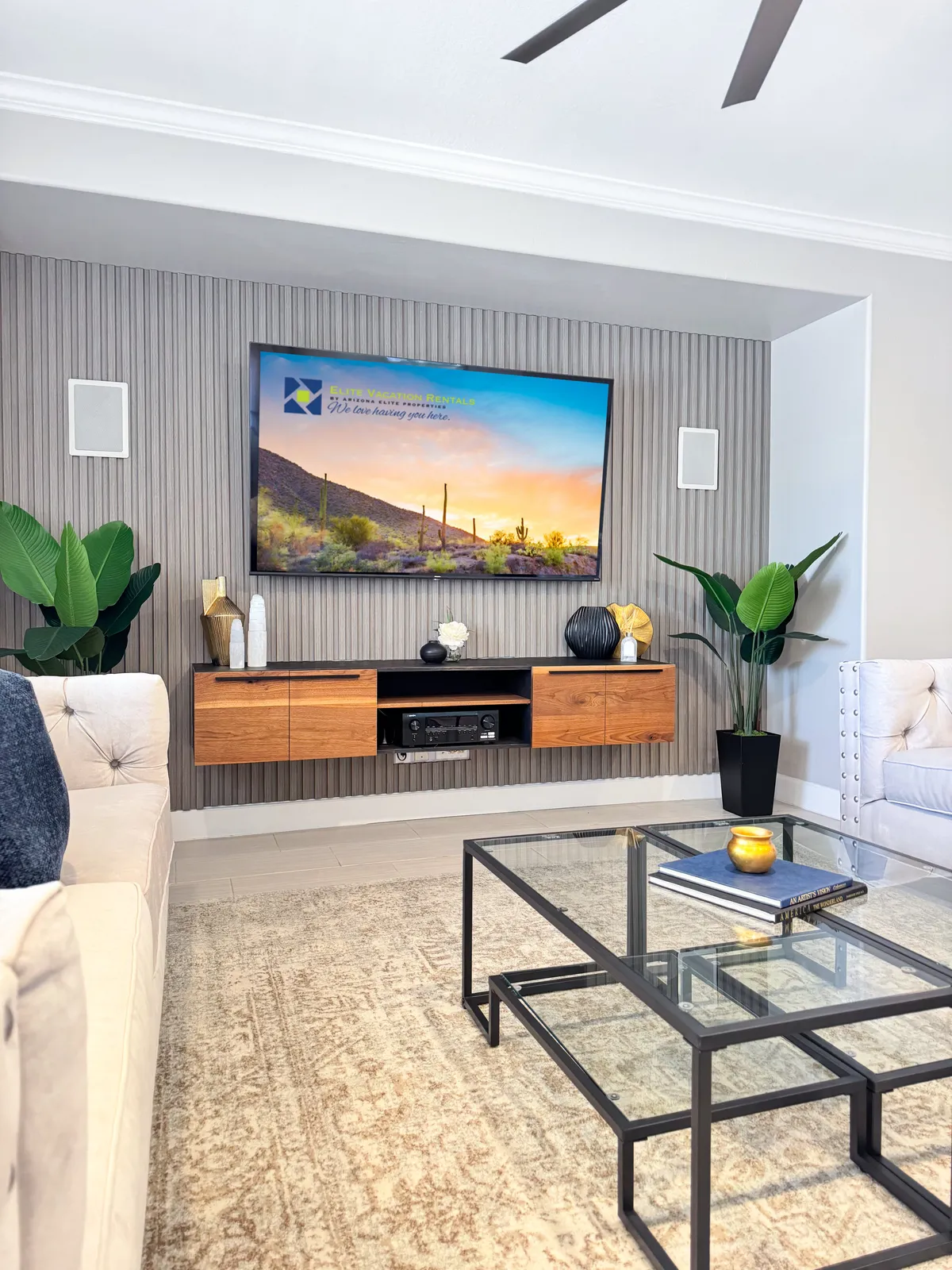 A stylish movie room with a sectional sofa, modern coffee table, decorative plants, and a TV displaying a scenic landscape. The ambiance is cozy and contemporary—ideal for movie nights or using the pull-out sectional as an additional sleeping area.