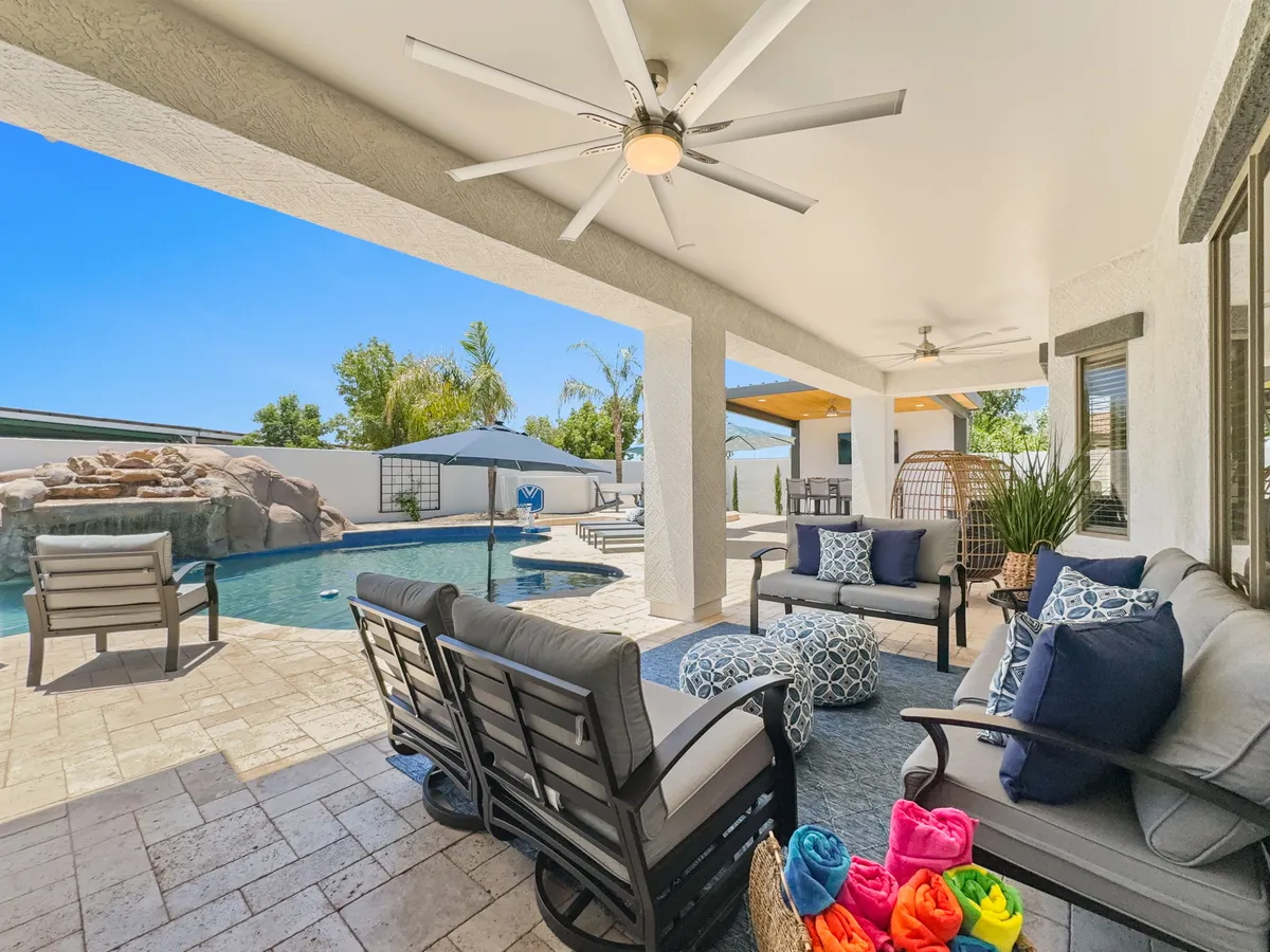 A sparkling swimming pool surrounded by comfortable outdoor seating, colorful towels, and lush greenery. The pool area is designed for relaxation or socializing, with water features and plenty of space for lounging or hosting gatherings.